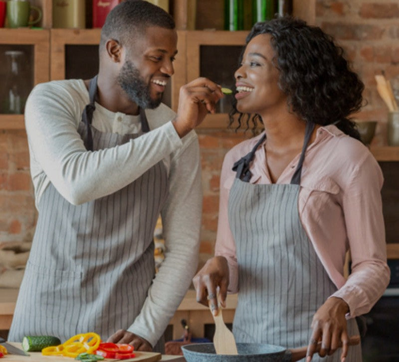 Couple cooking together in kitchen wearing aprons enjoying meal prep Best Sellers Home and Kitchen